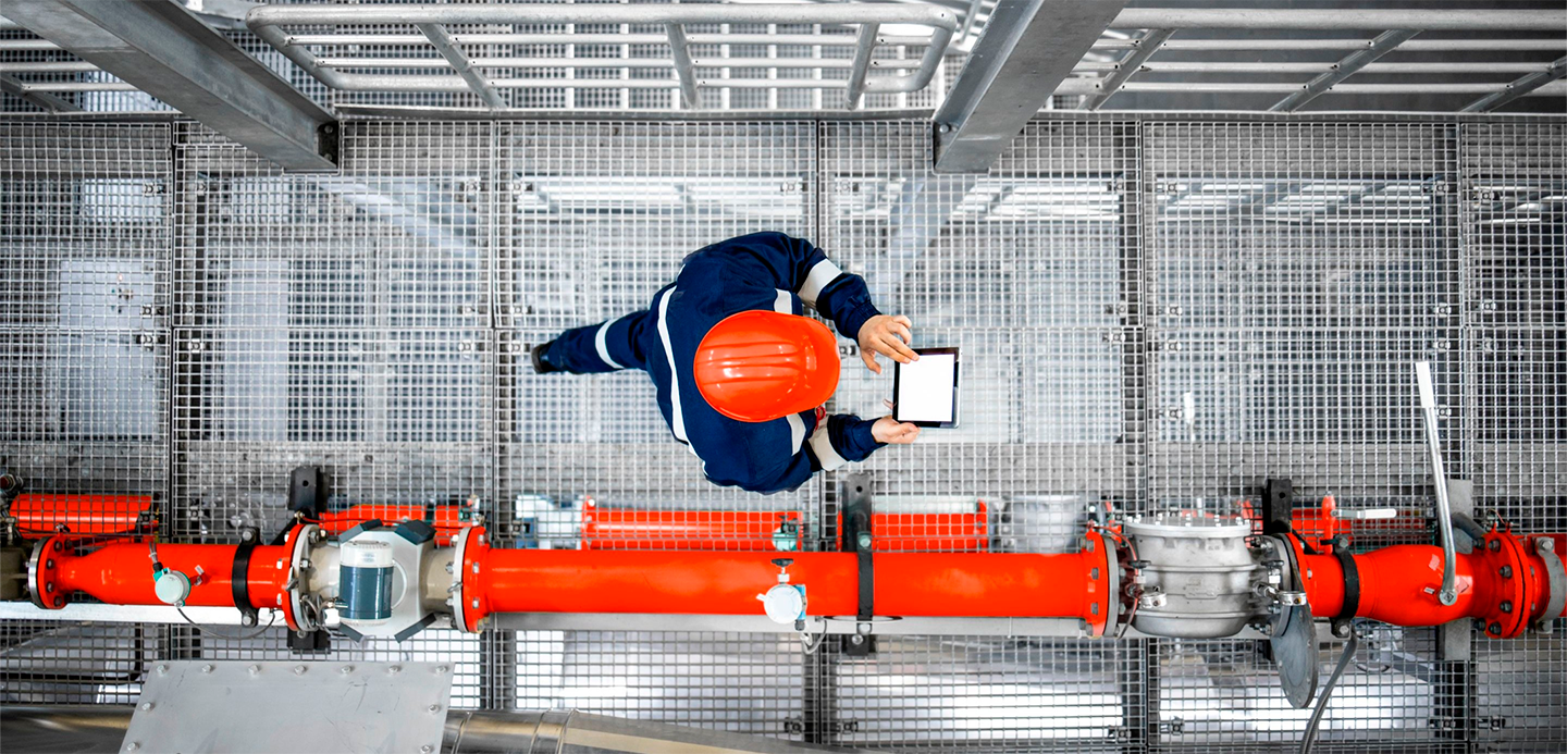 Worker in hard hat reviewing pipes and checking screen Worker in hard hat reviewing pipes and checking screen