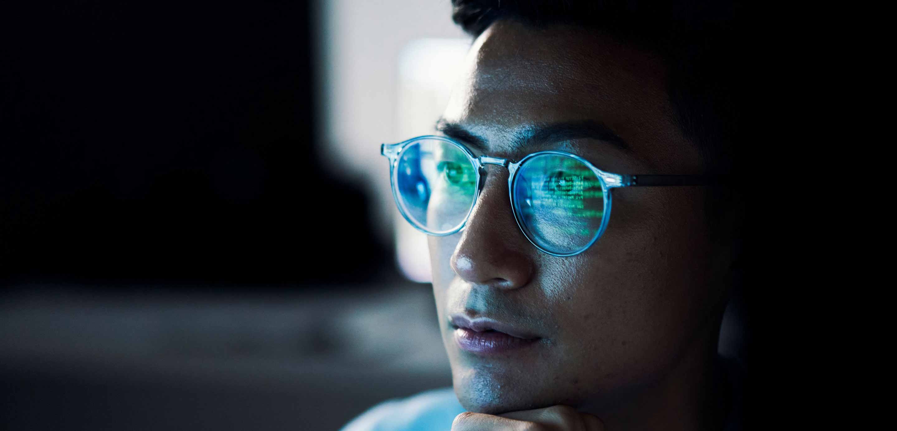 Man viewing computer screen with data reflecting in his glasses. Man viewing computer screen with data reflecting in his glasses.