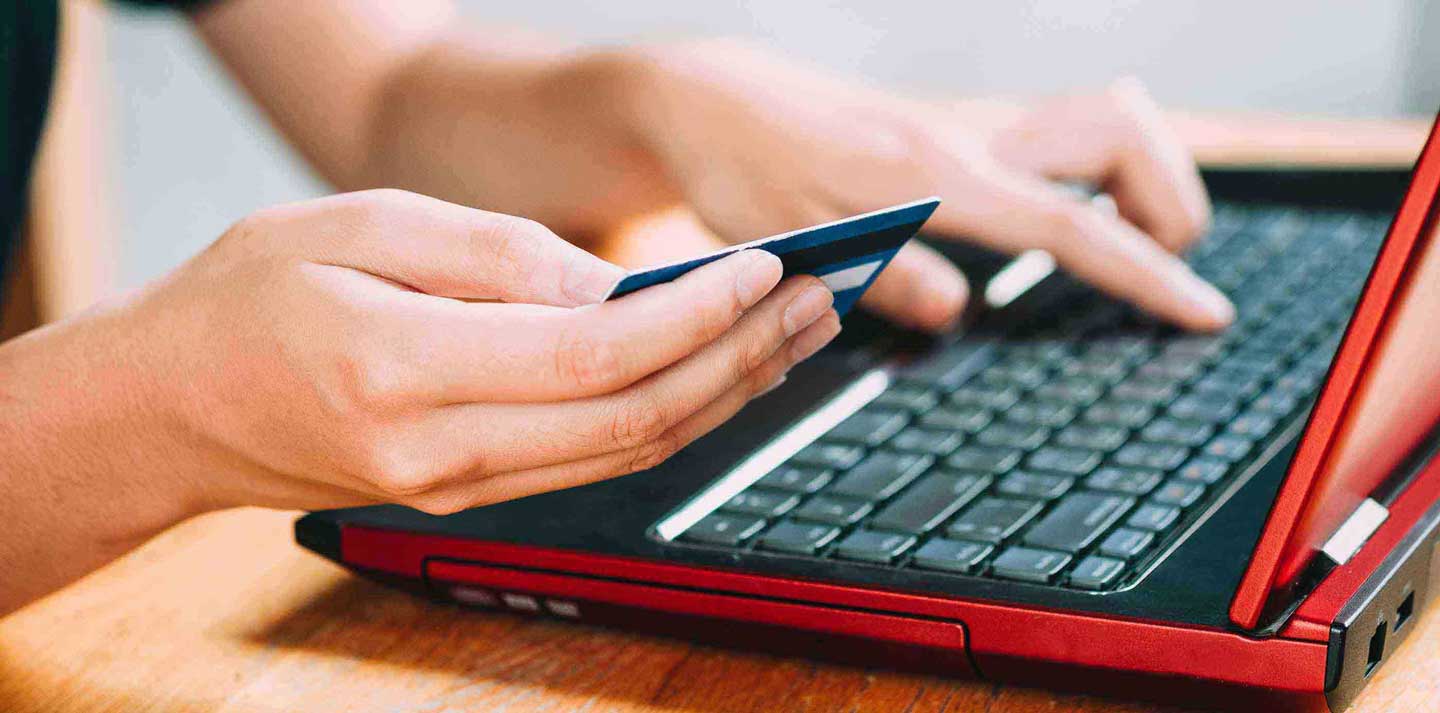 Woman entering credit card details onto a laptop Woman entering credit card details onto a laptop